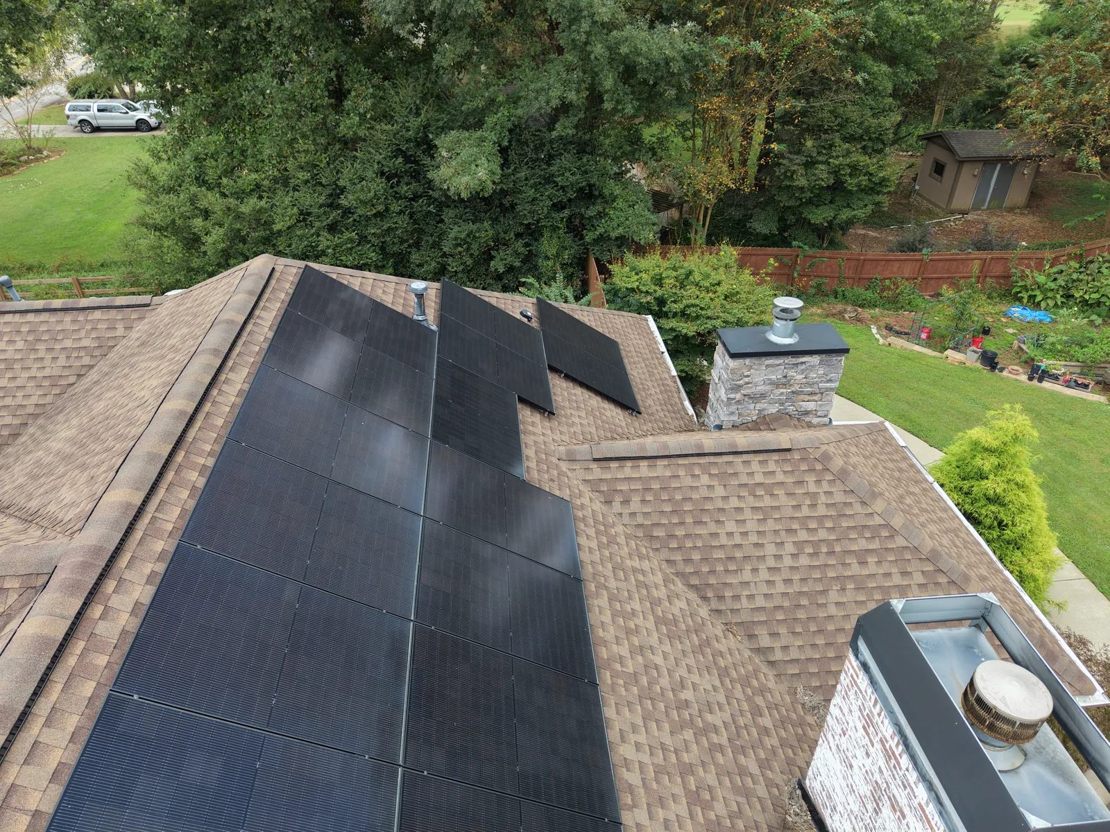 Shingle roof with solar panels, a chimney, and rooftop vents